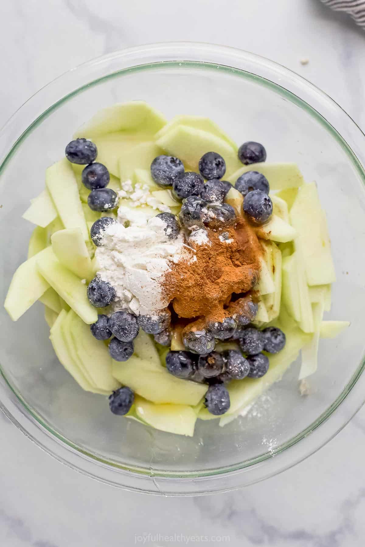 fresh apples and blueberries in a bowl with flour and cinnamon