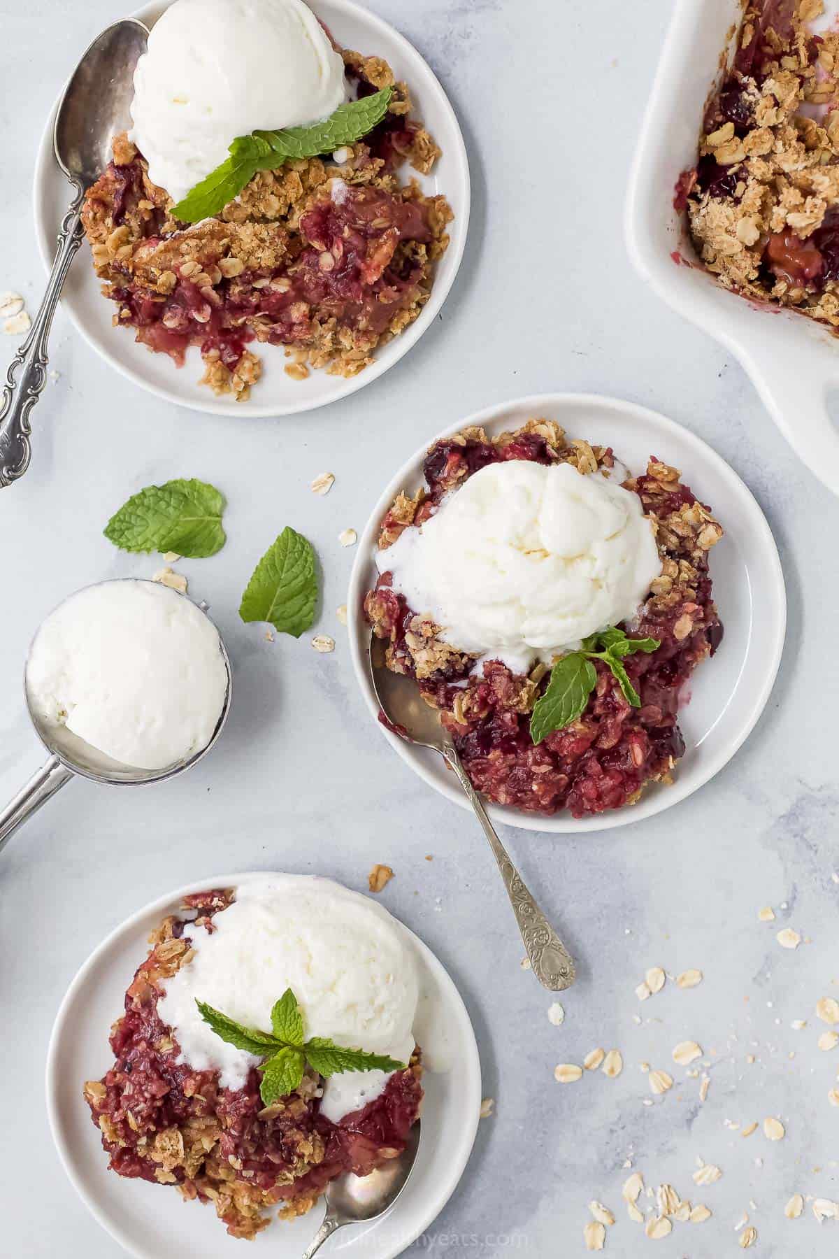 three plates with apple blueberry crumble topped with ice cream