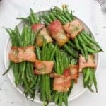 A plate piled high with green bean bundles on top of a marble countertop