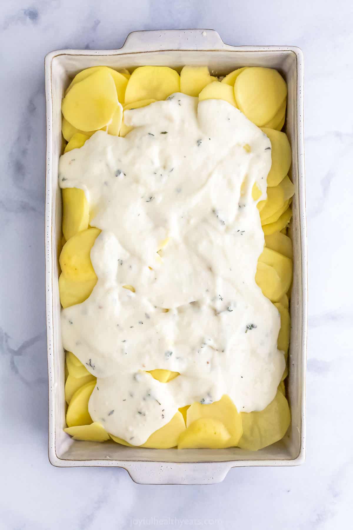 layering potatoes and cheese sauce for scalloped potatoes