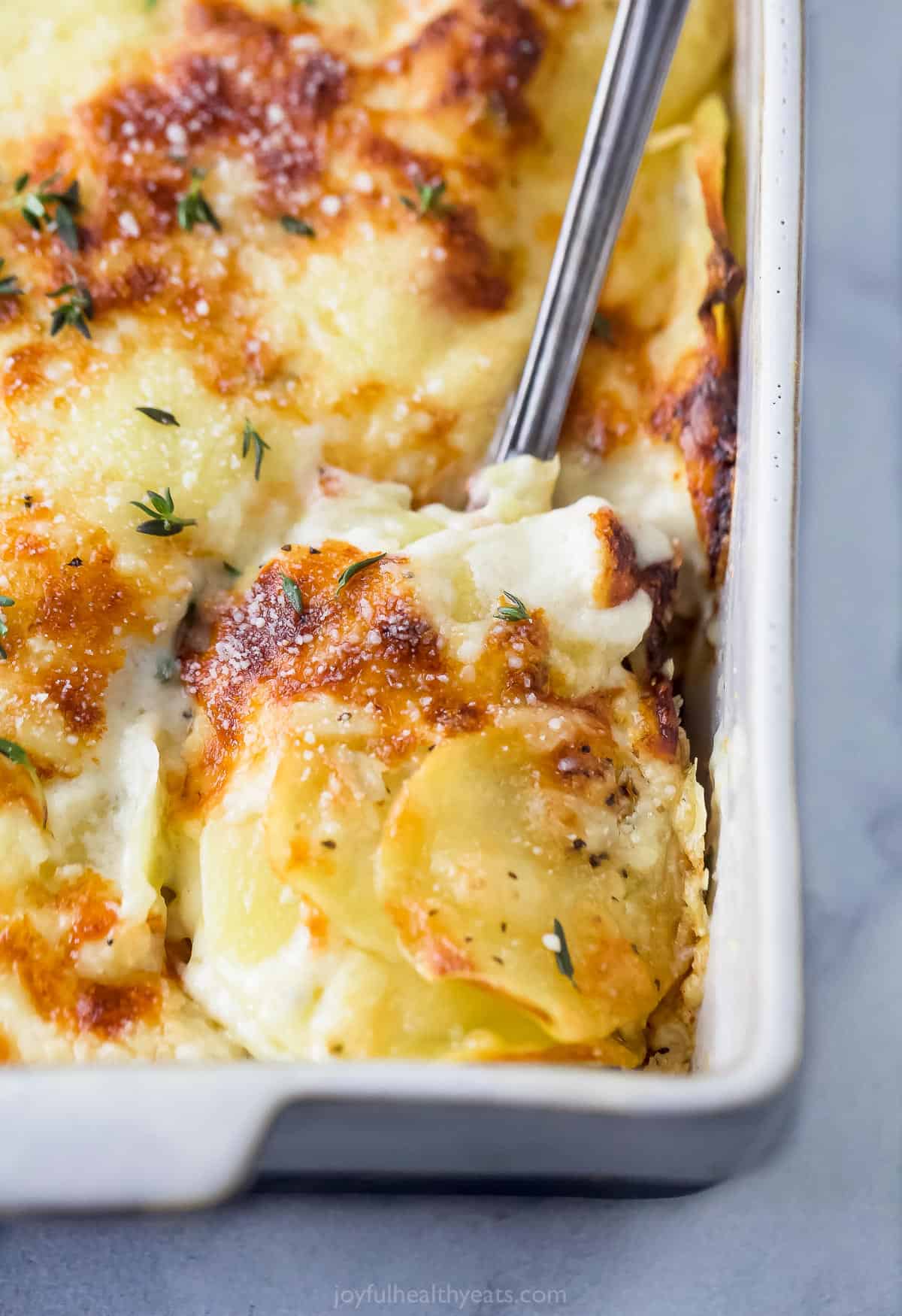 spoon scooping cheesy scalloped potatoes