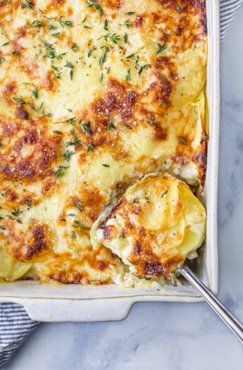 spoon scooping cheesy scalloped potatoes