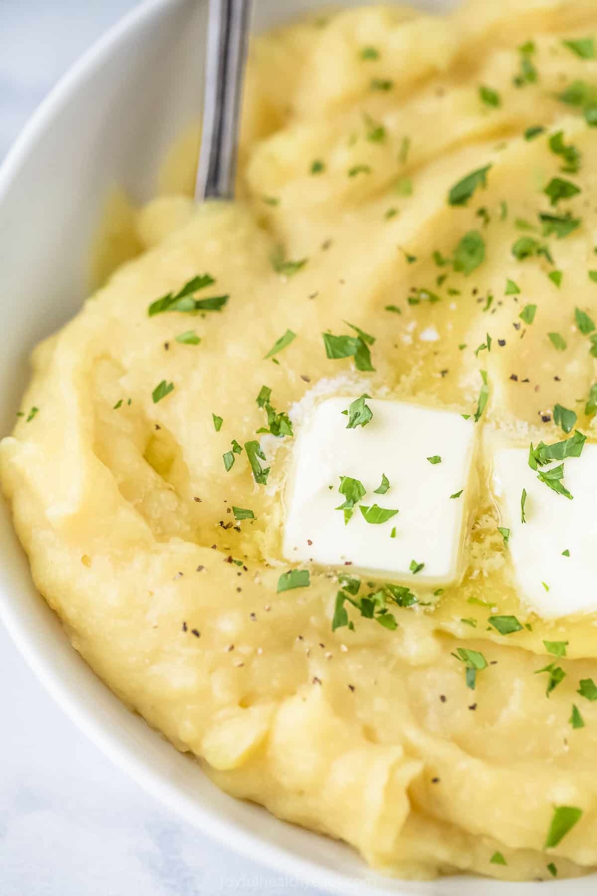 A close-up shot of creamy parsnip puree in a bowl with a spoon inside