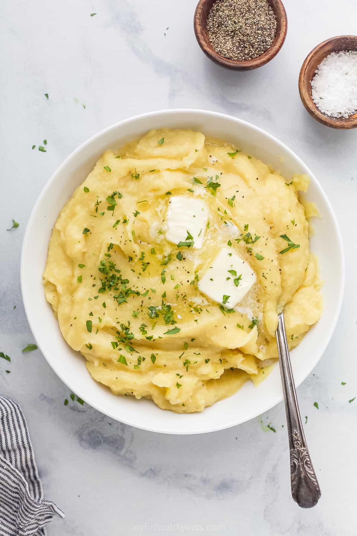 A big bowl of pureed parsnip on a countertop with two small dishes of salt and pepper