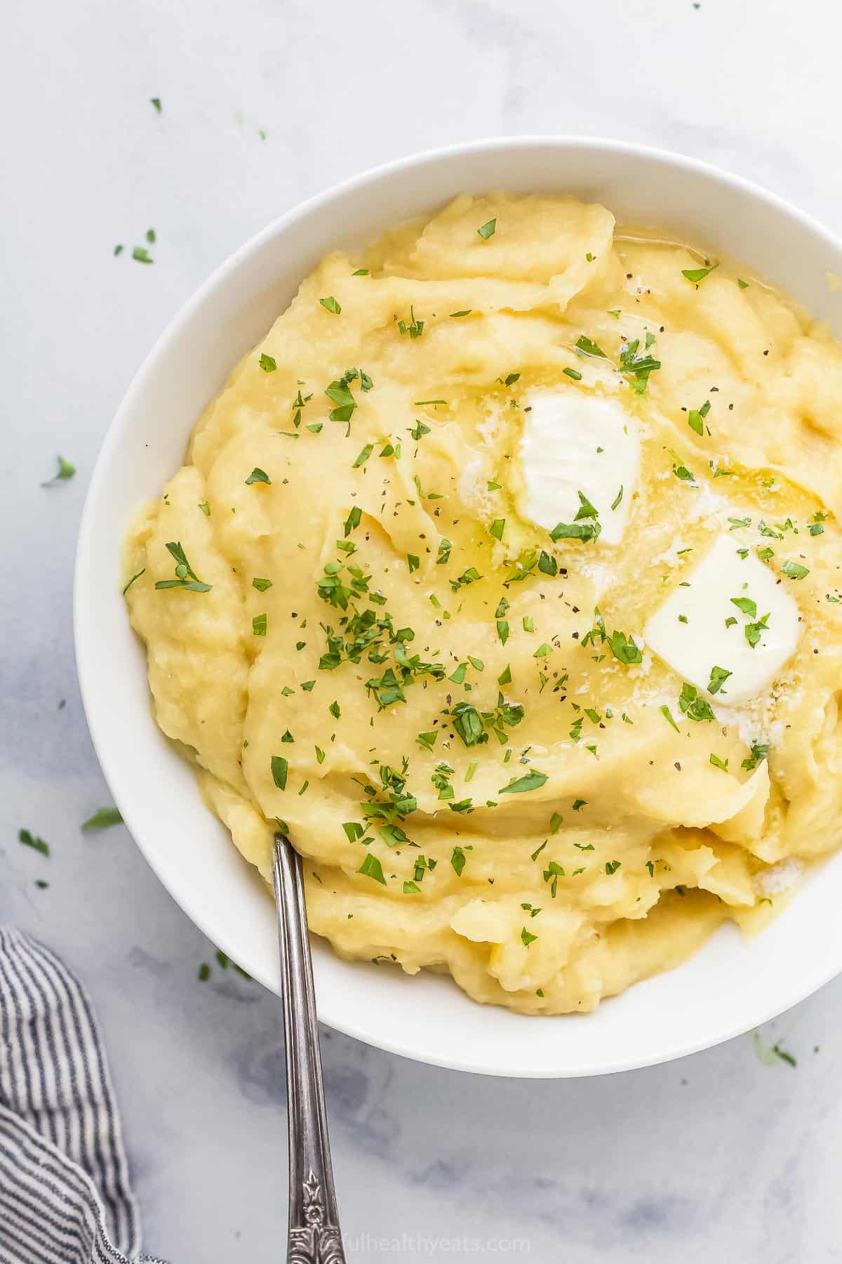 A serving bowl full of parsnip puree with a metal fork inside