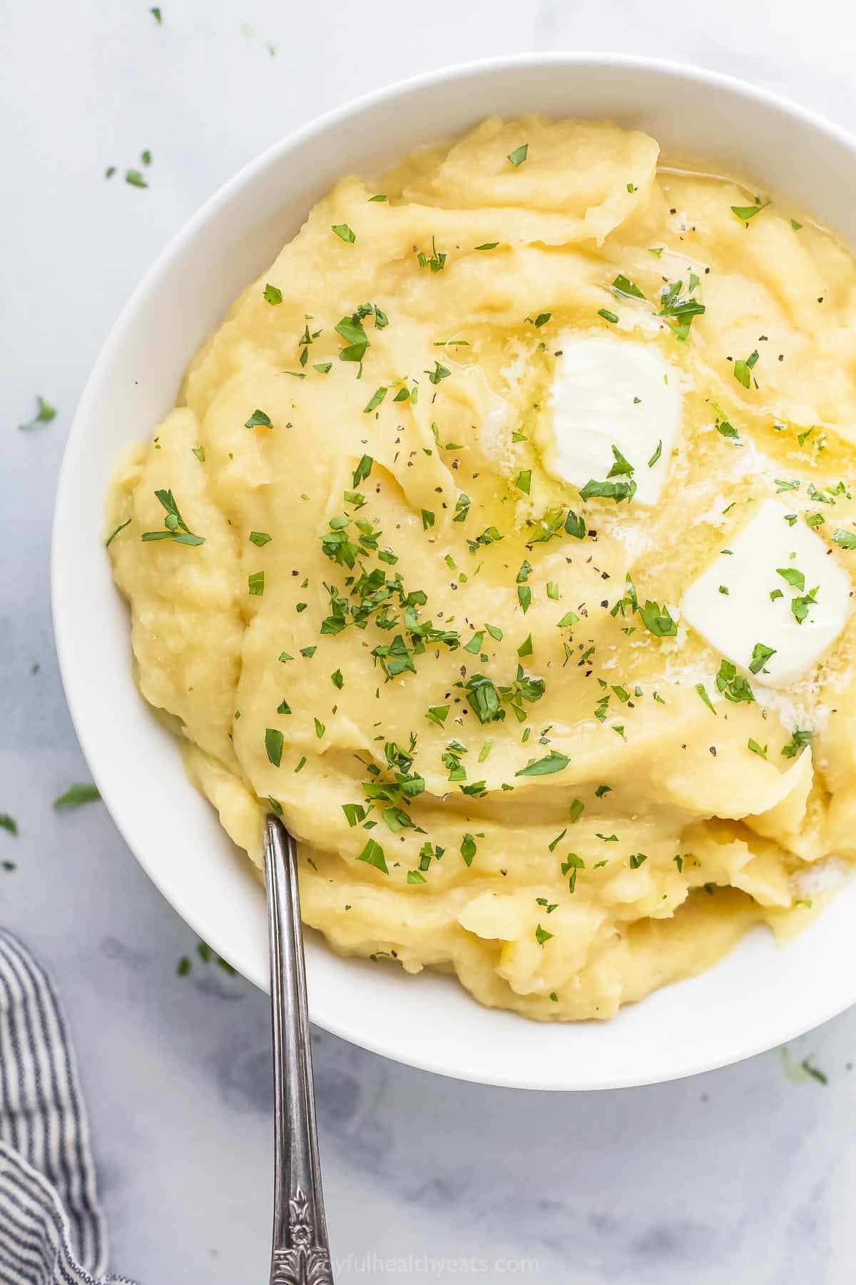 A bowl of mashed parsnip and potatoes sitting on a marble countertop