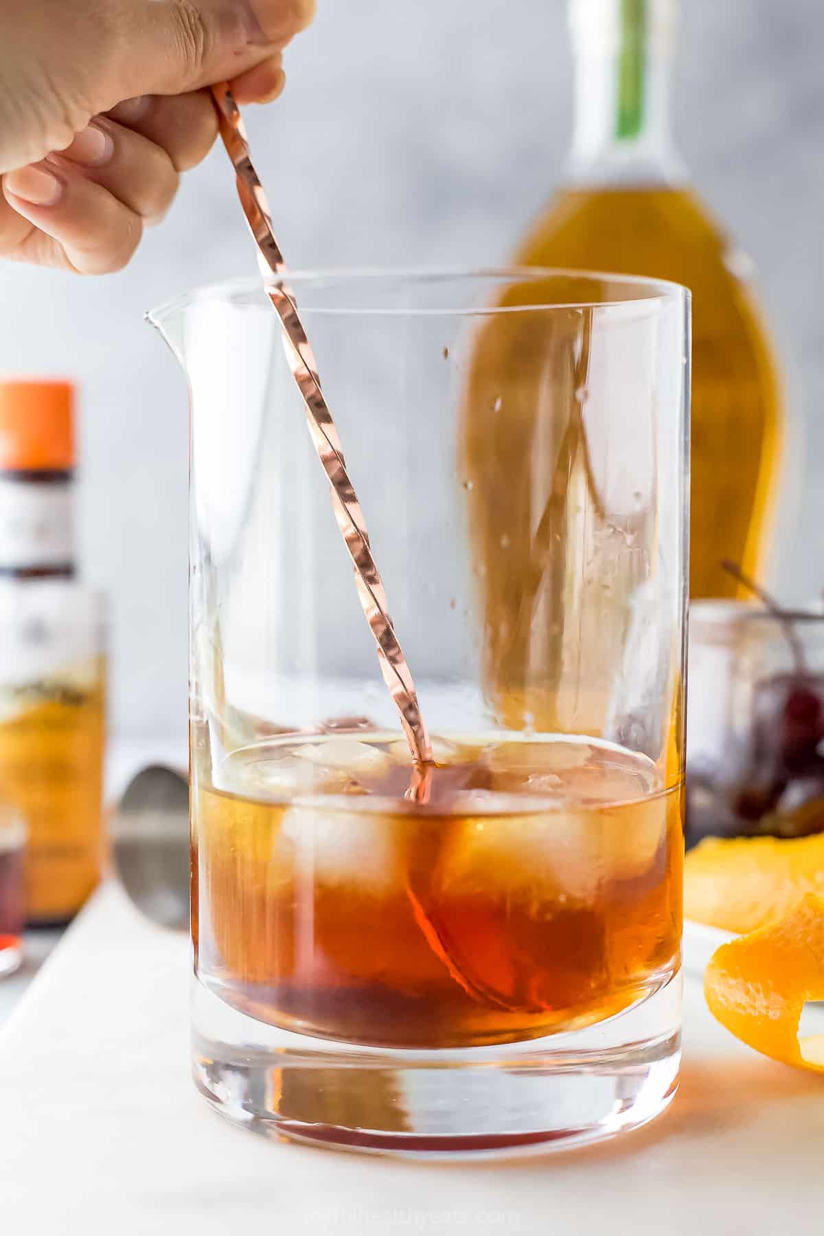 A stirrer being used to mix the old fashioned ingredients together in a cocktail shaker