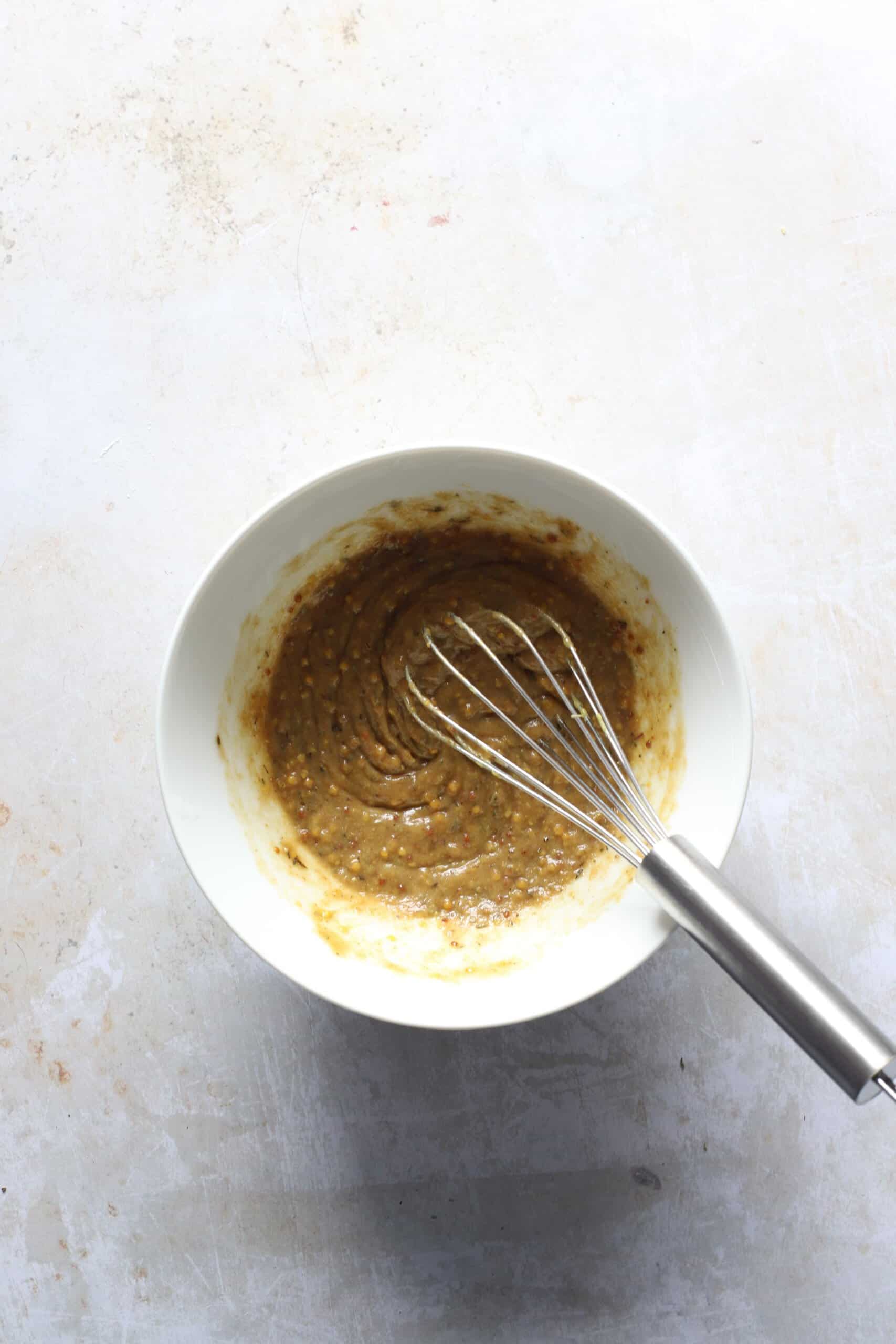 The combined seasonings in a small white bowl with a metal whisk