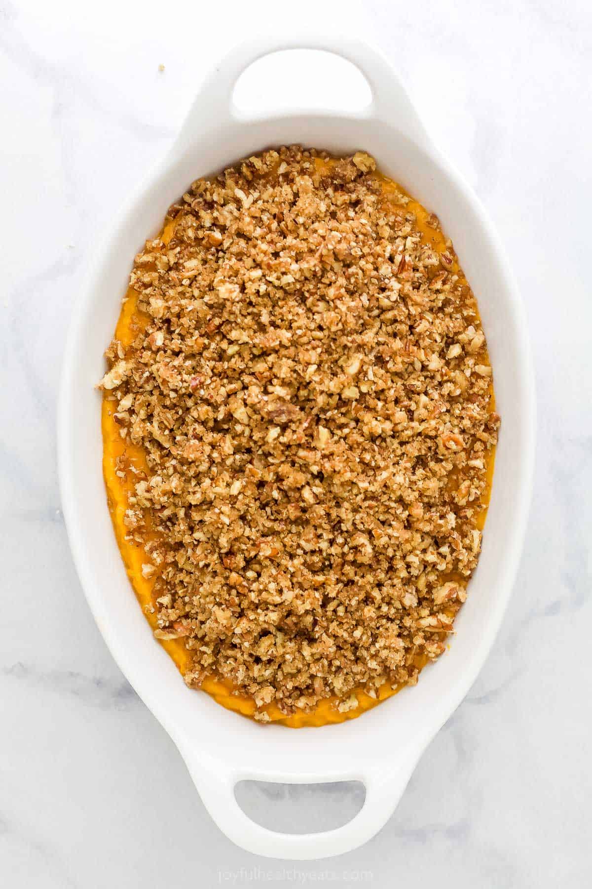 The prepared sweet potato filling in a casserole dish with the unbaked pecan streusel on top