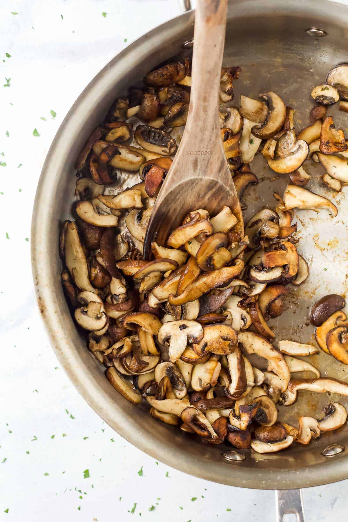 Sliced baby bella and shiitake mushrooms in a large metal sauté pan