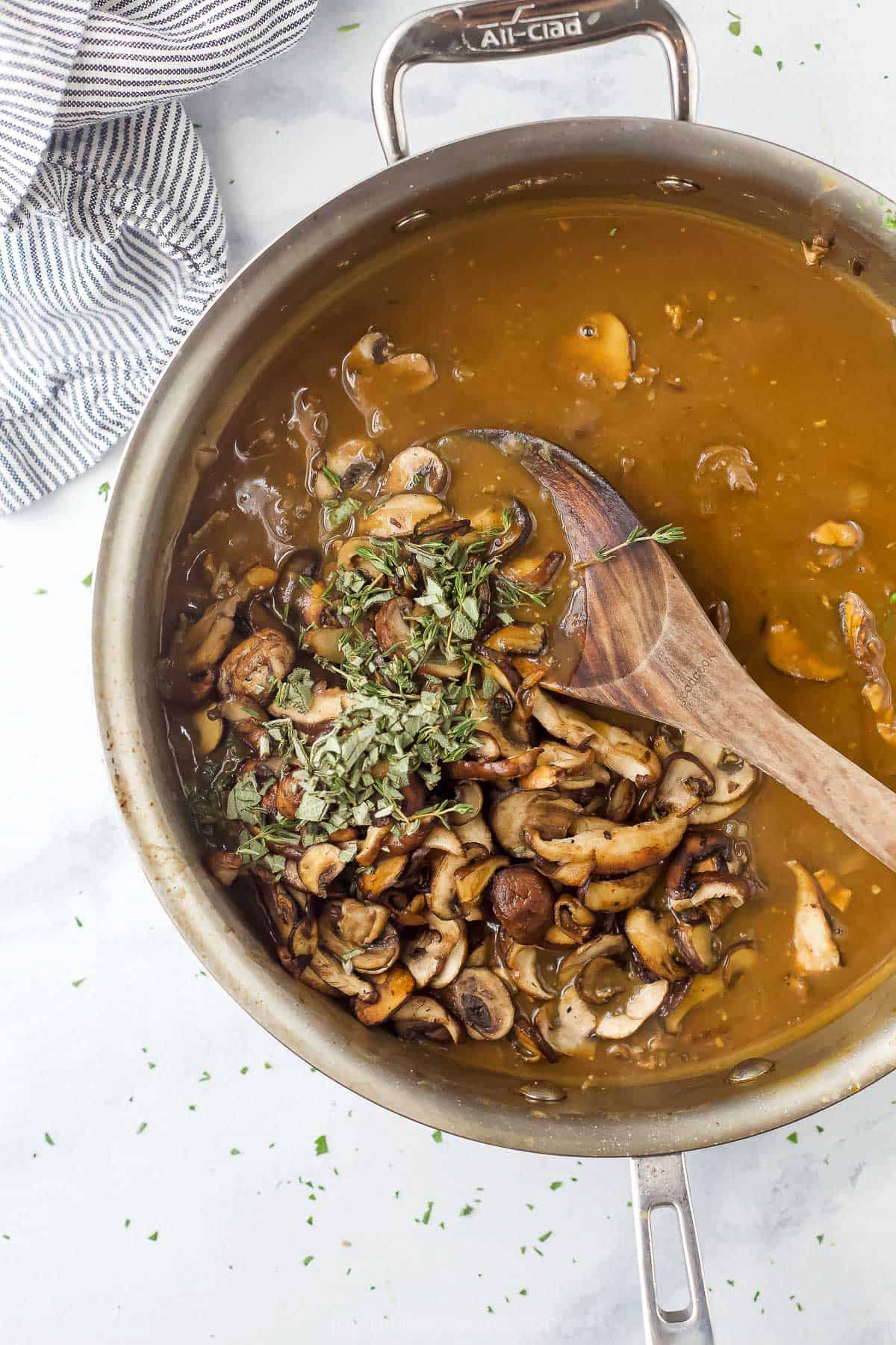 Chopped sage, chopped thyme, salt and pepper being stirred into the sauce