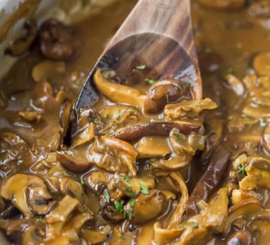 A wooden spoon digging into a pot of freshly-made mushroom gravy