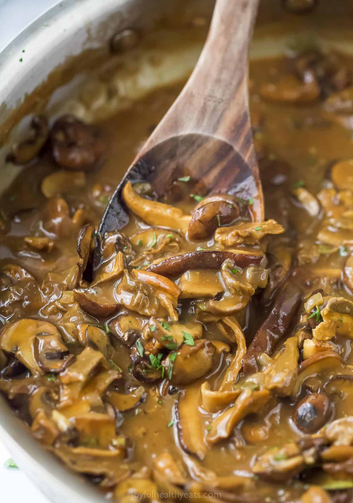 A wooden spoon digging into a pot of freshly-made mushroom gravy