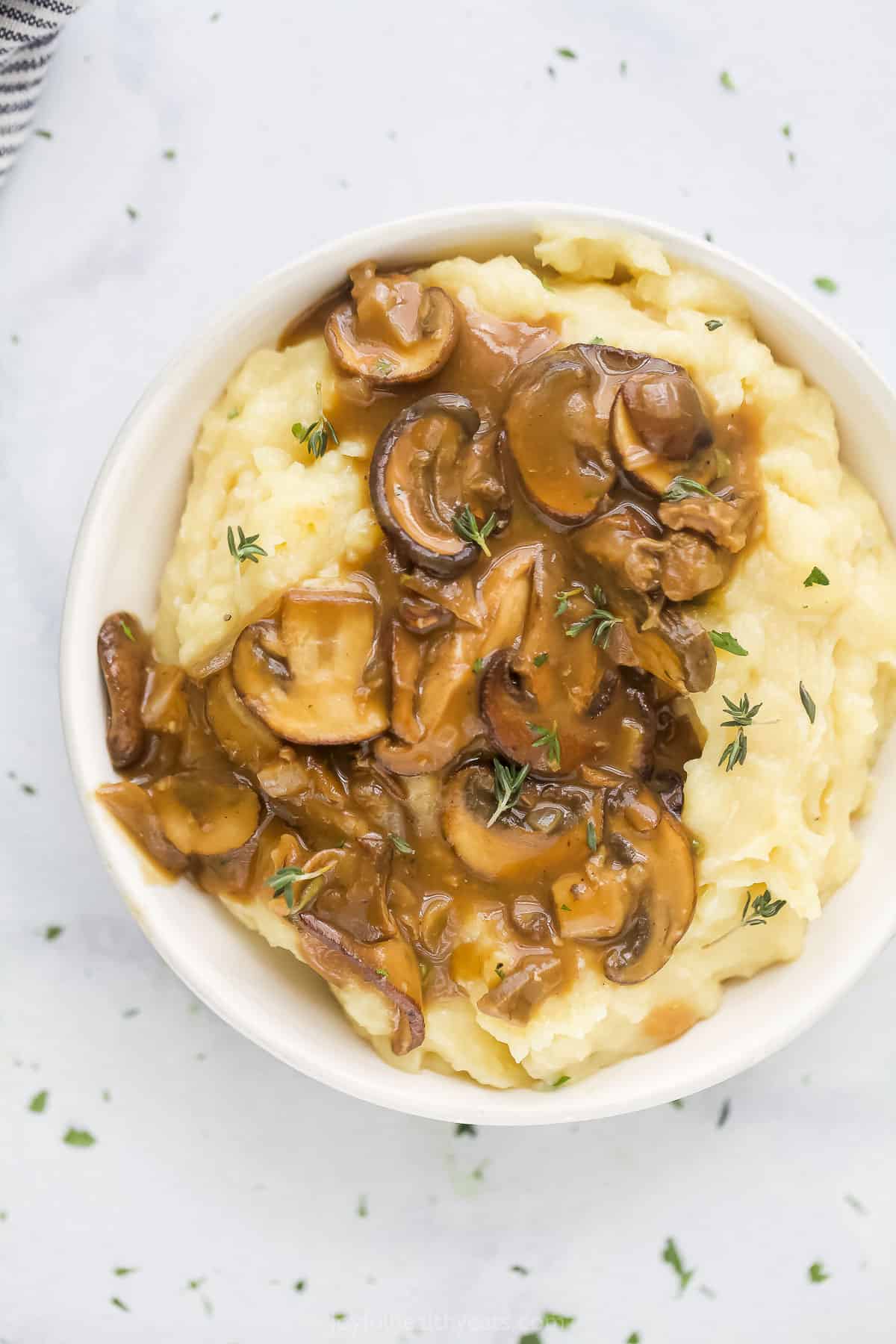 A bowl of mashed potatoes topped with a helping of mushroom gravy