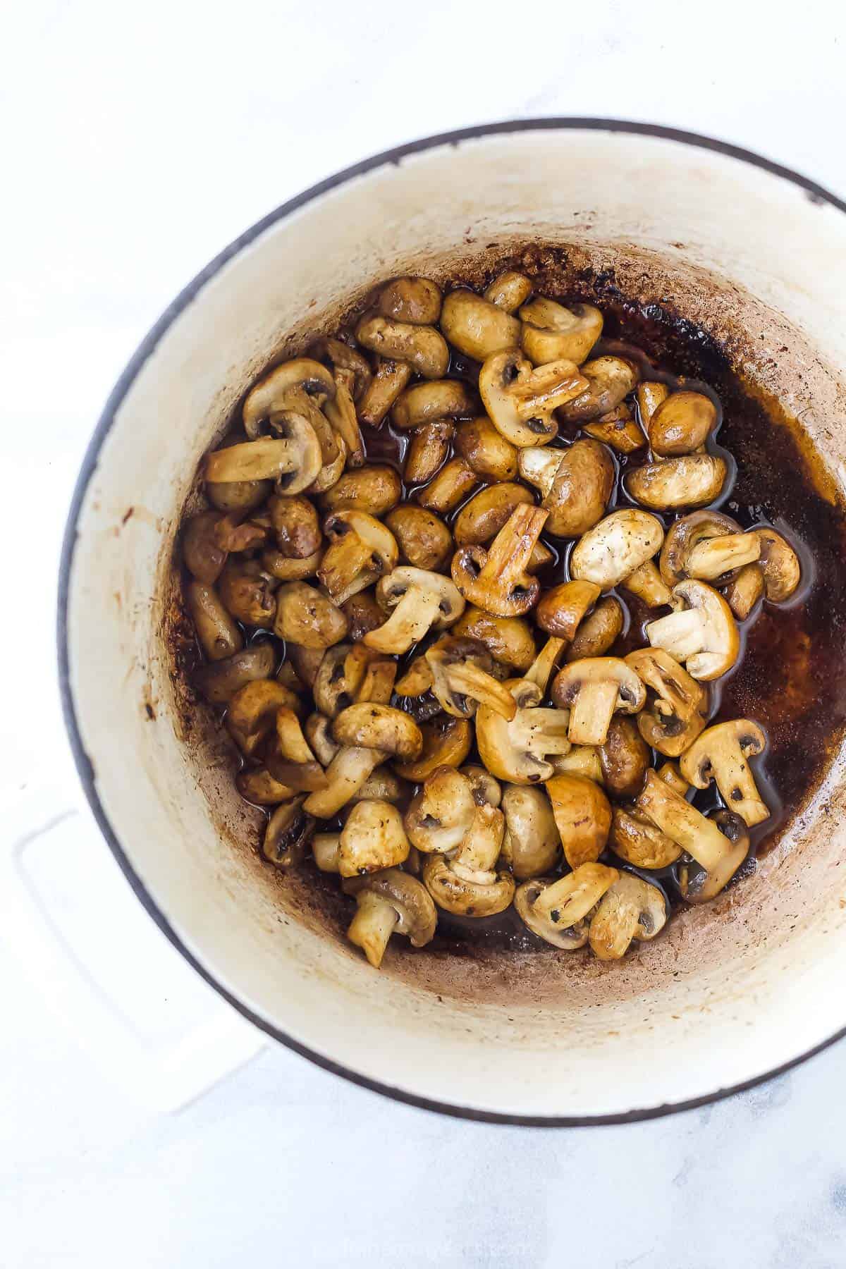 Chopped button mushrooms inside of a white dutch oven