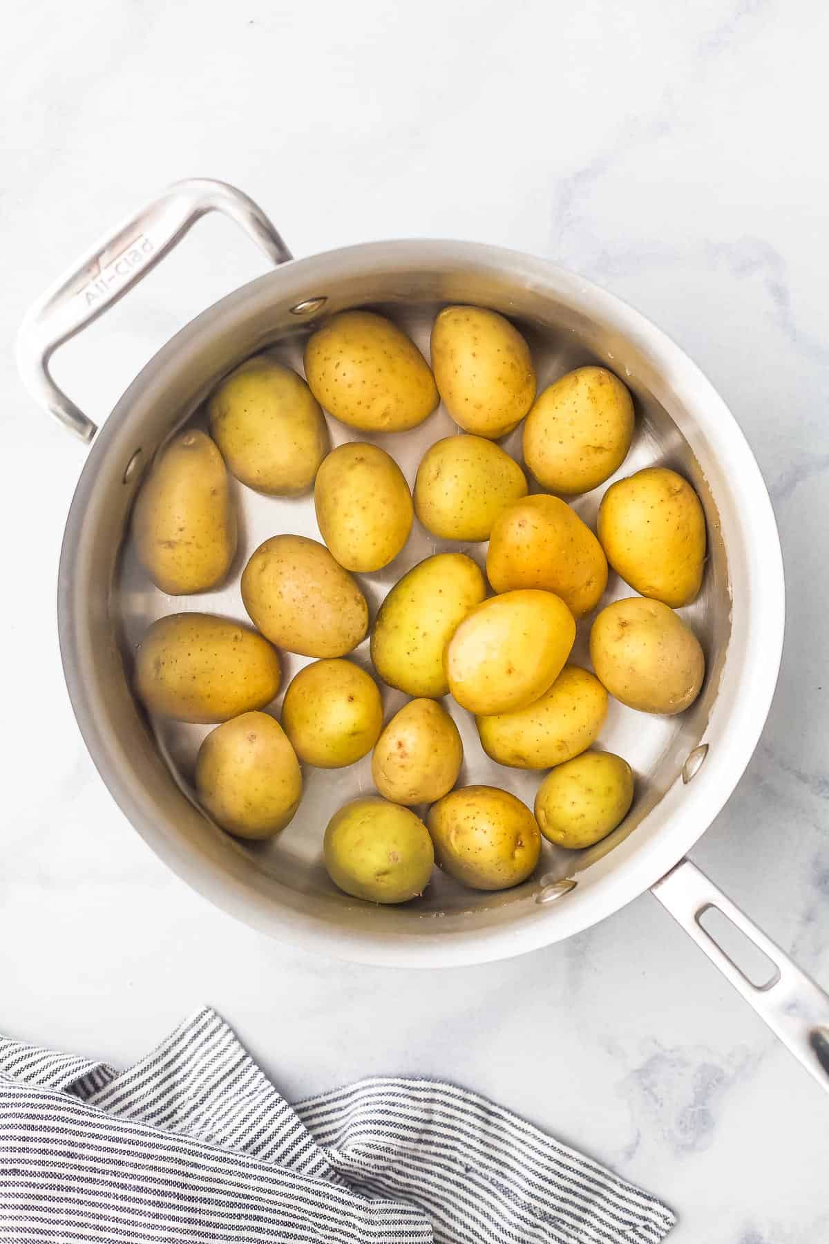 Mini potatoes being boiled in a large metal saucepan
