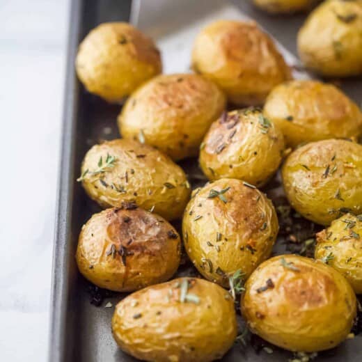 A close-up shot of crispy oven-baked garlic herb potatoes on a metal baking sheet