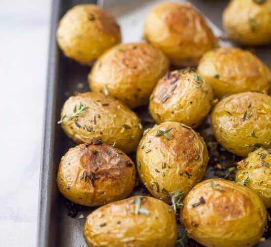 A close-up shot of crispy oven-baked garlic herb potatoes on a metal baking sheet