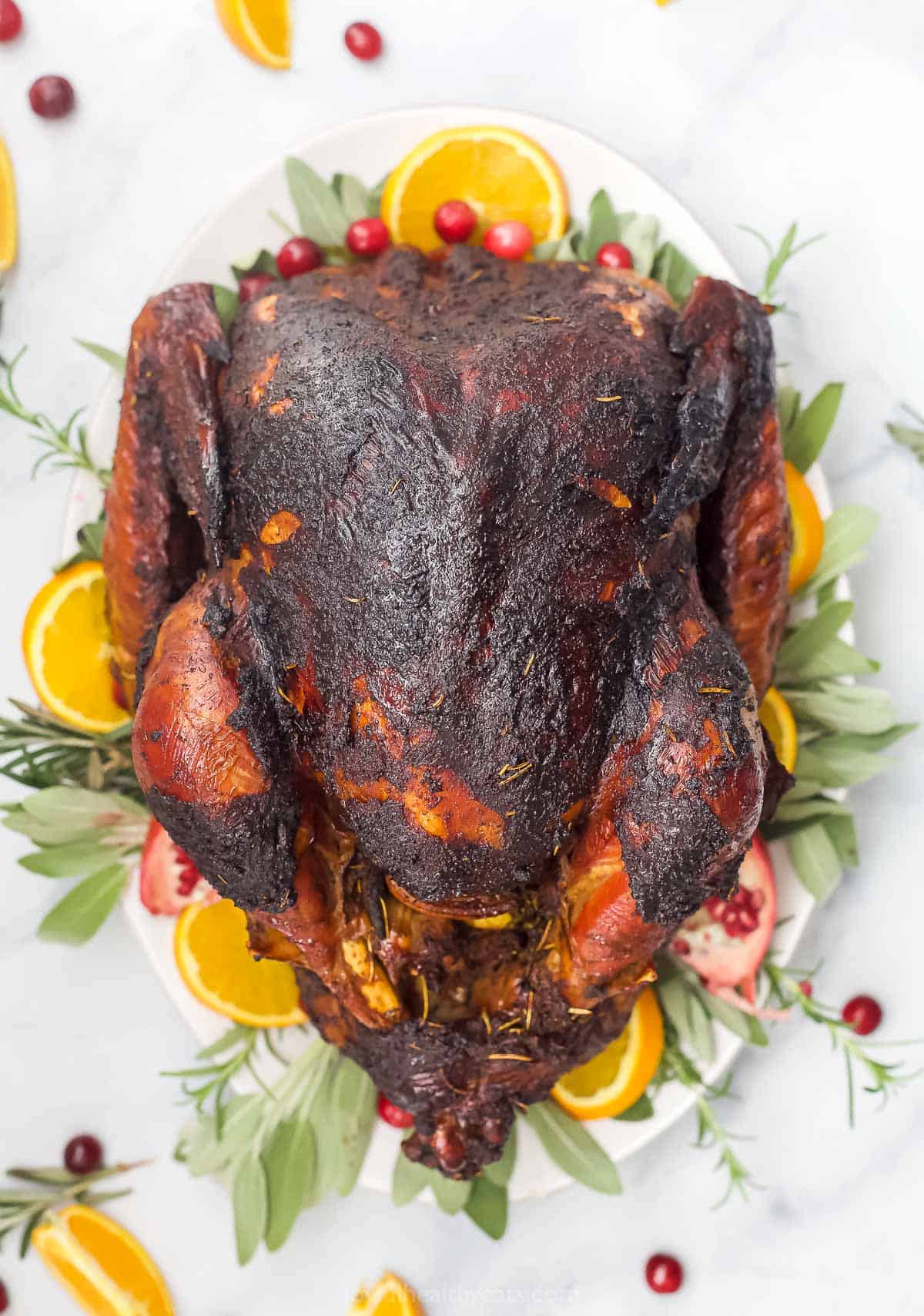 a whole maple smoked turkey on a platter with oranges and cranberries