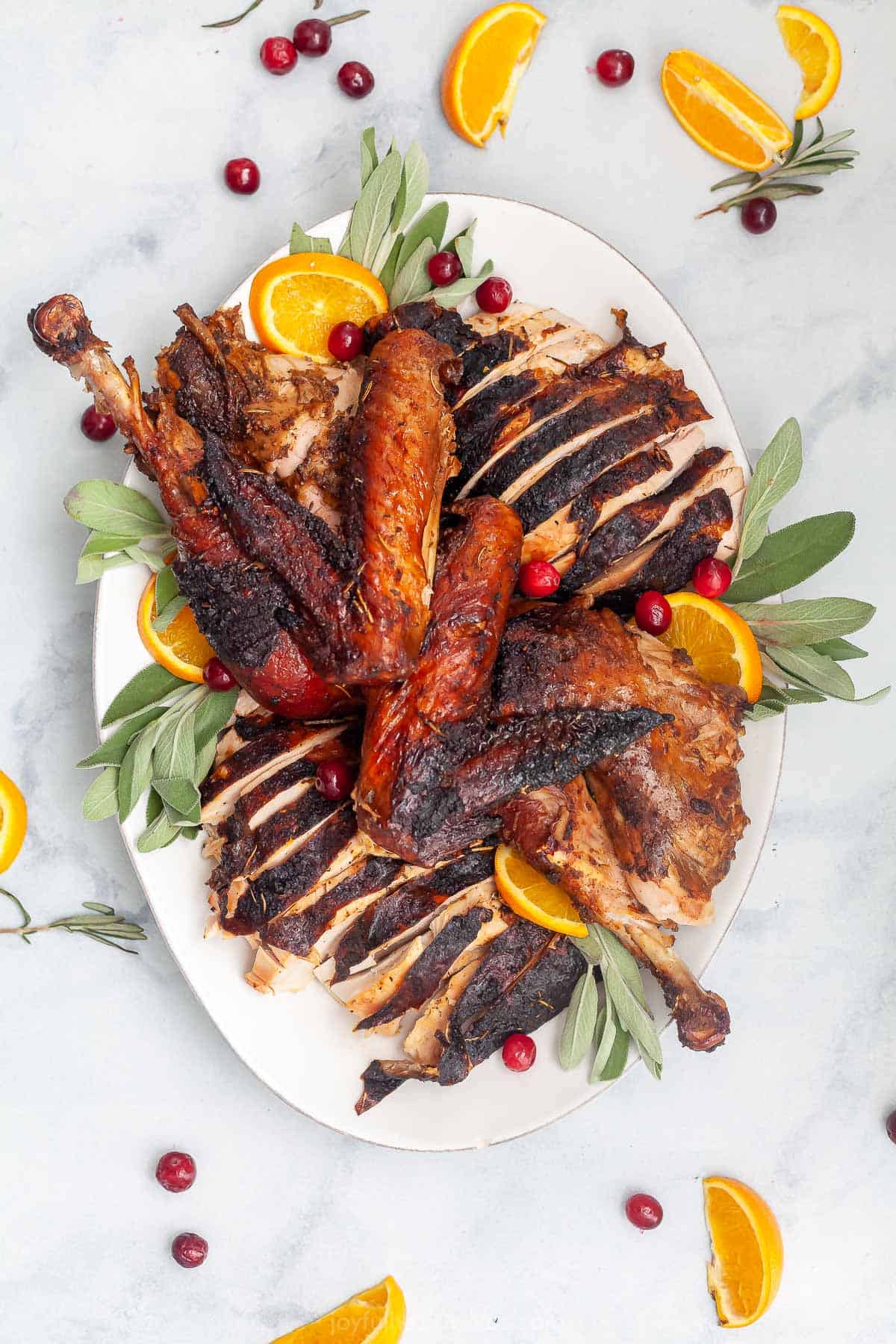 sliced smoked turkey on a platter with oranges and cranberries