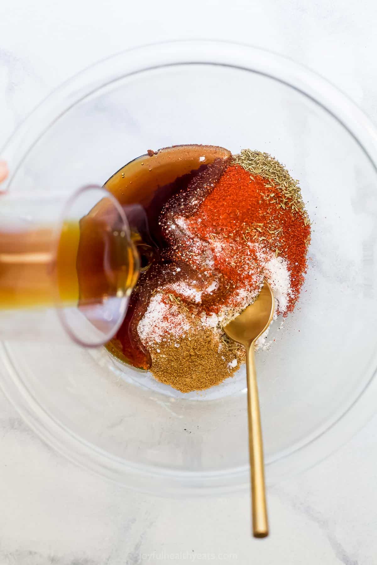 spices in a bowl with maple being poured in