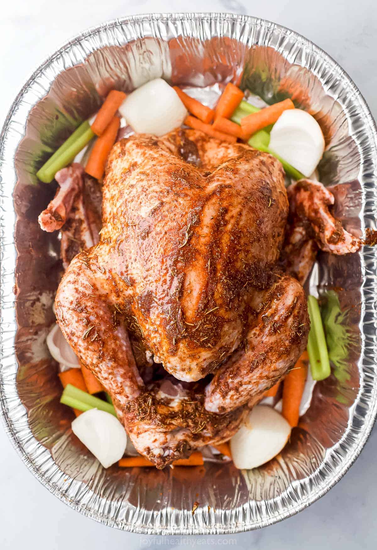 seasoned turkey in a roasted pan with veggies