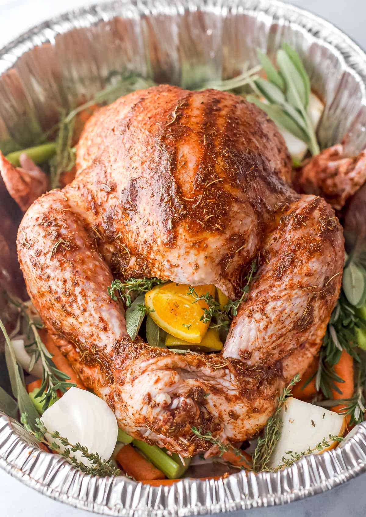 seasoned whole turkey in a roasting pan stuffed with citrus