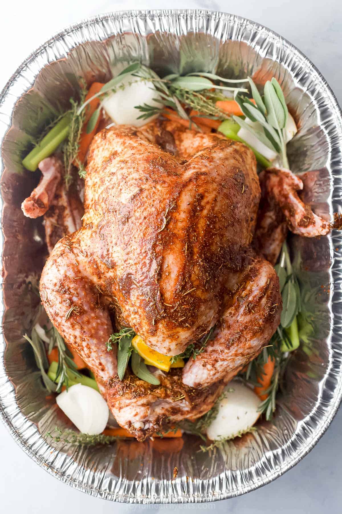 whole seasoned turkey in a roasted pan with vegetables and herbs