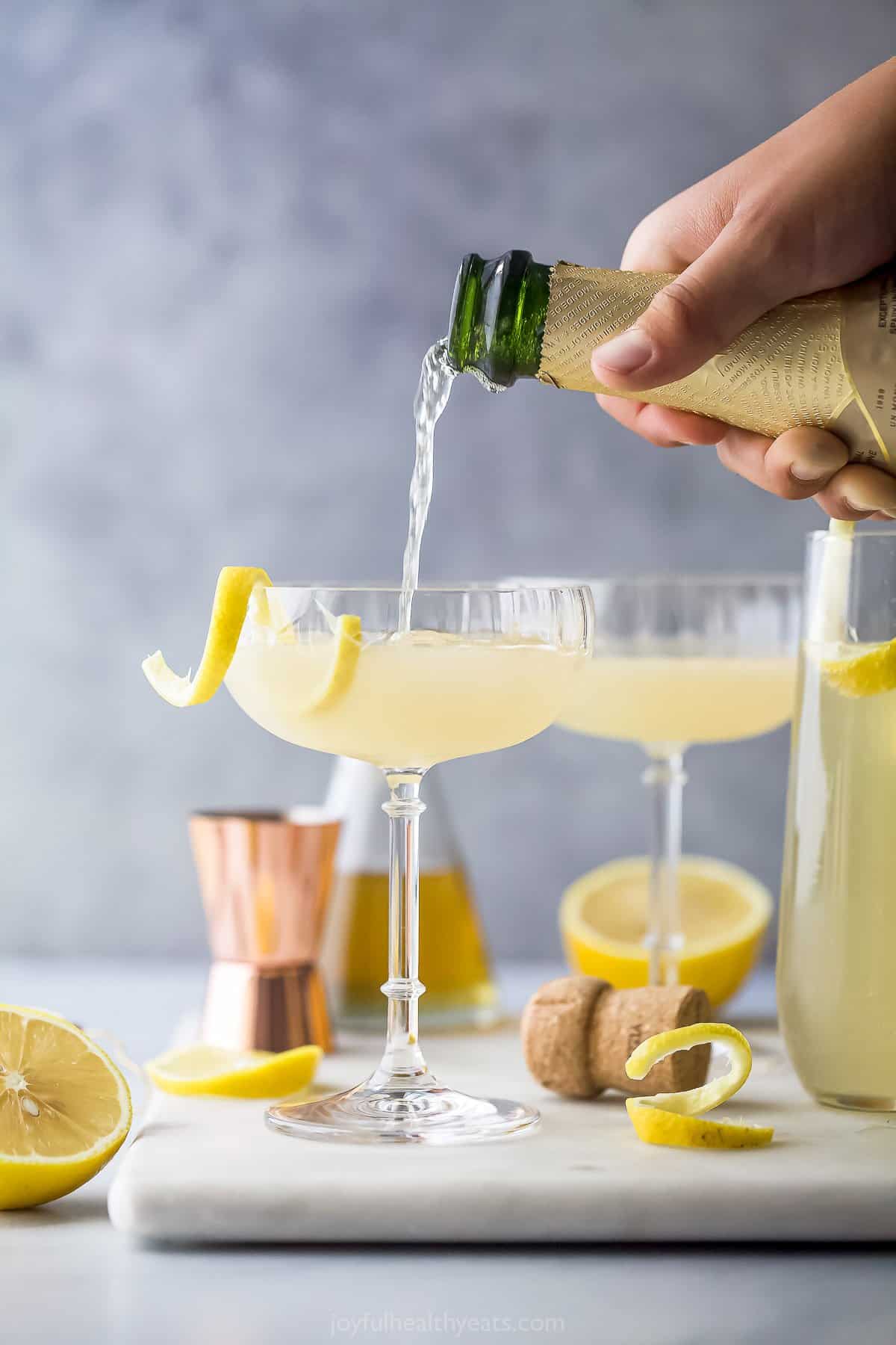 Champagne being poured into a glass containing the shaken French 75 ingredients