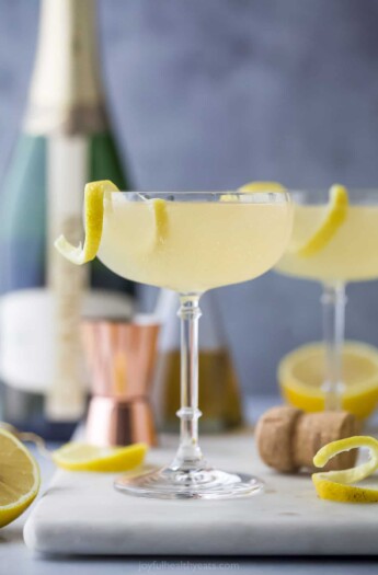 A French 75 cocktail on a kitchen countertop beside a cork and a cocktail measurer