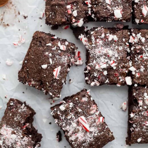 Nine homemade candy cane brownies on a countertop with a small amount of cinnamon beside them