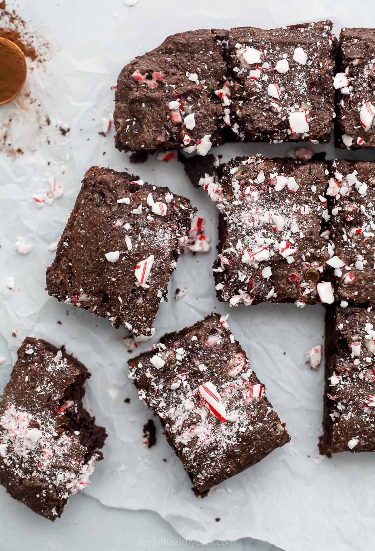 Nine homemade candy cane brownies on a countertop with a small amount of cinnamon beside them