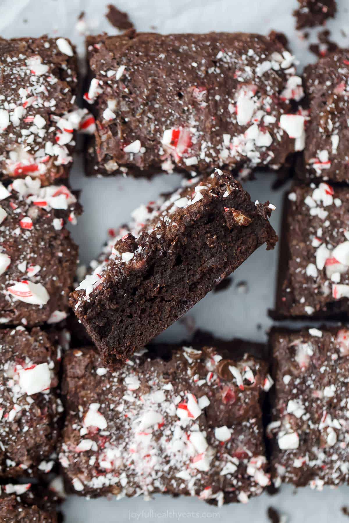 Peppermint brownies arranged on a sheet of parchment paper with one laying on its side