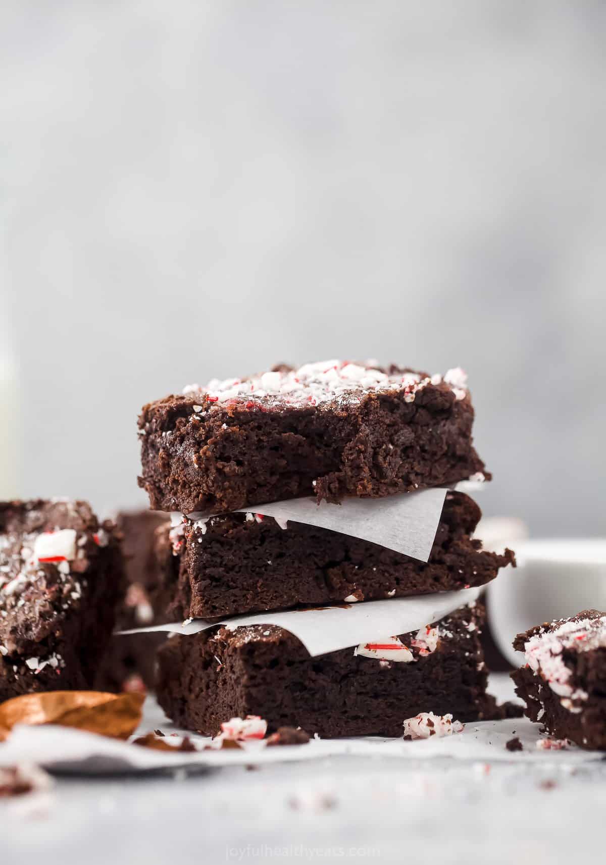 A stack of three peppermint brownies with a piece of parchment paper between each one