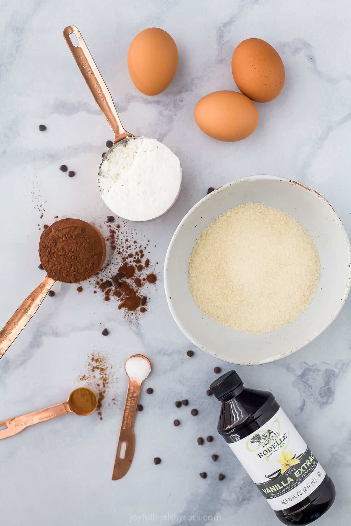 Eggs, vanilla extract, cinnamon, flour and the remaining ingredients arranged on a marble countertop