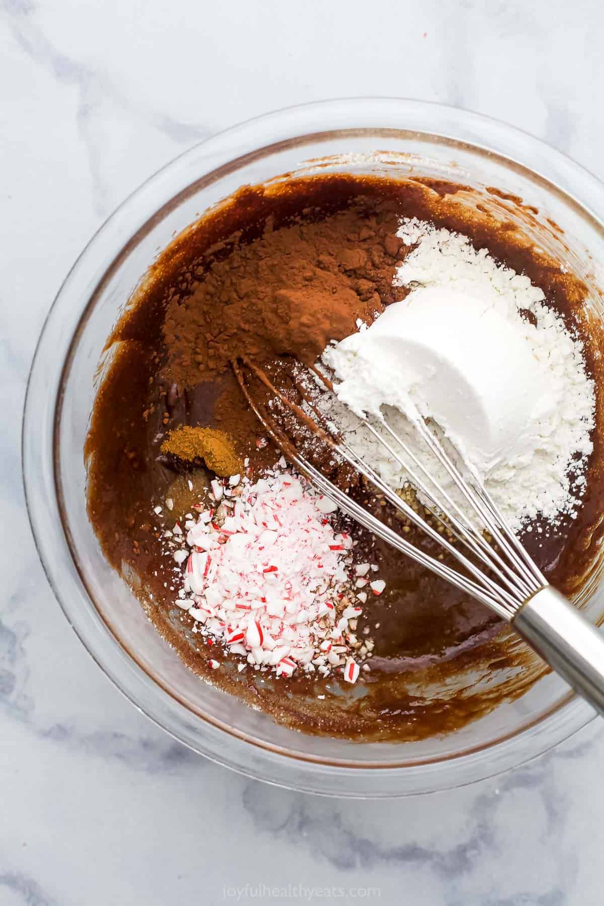 A bowl of brownie batter with the dry ingredients and crushed candy canes just added