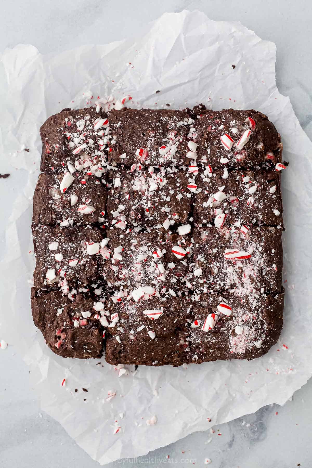 The cooked and cooled brownies on the sheet of parchment paper after they've been removed from the pan