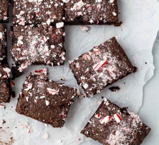 A batch of fudgy brownies on a piece of parchment paper over a marble surface