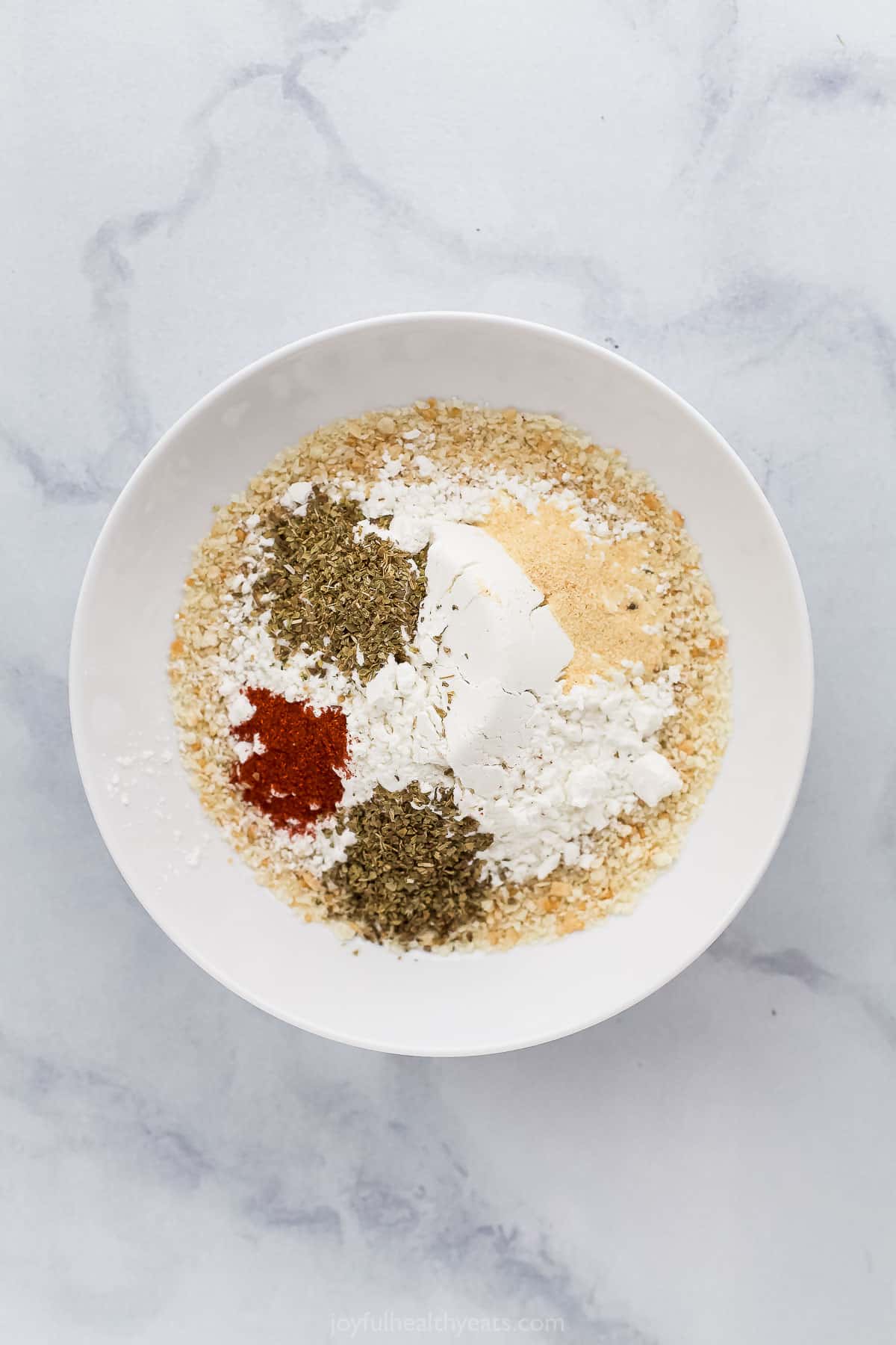 Dried herbs, gluten-free flour, smoked paprika and the rest of the dry ingredients inside of a mixing bowl