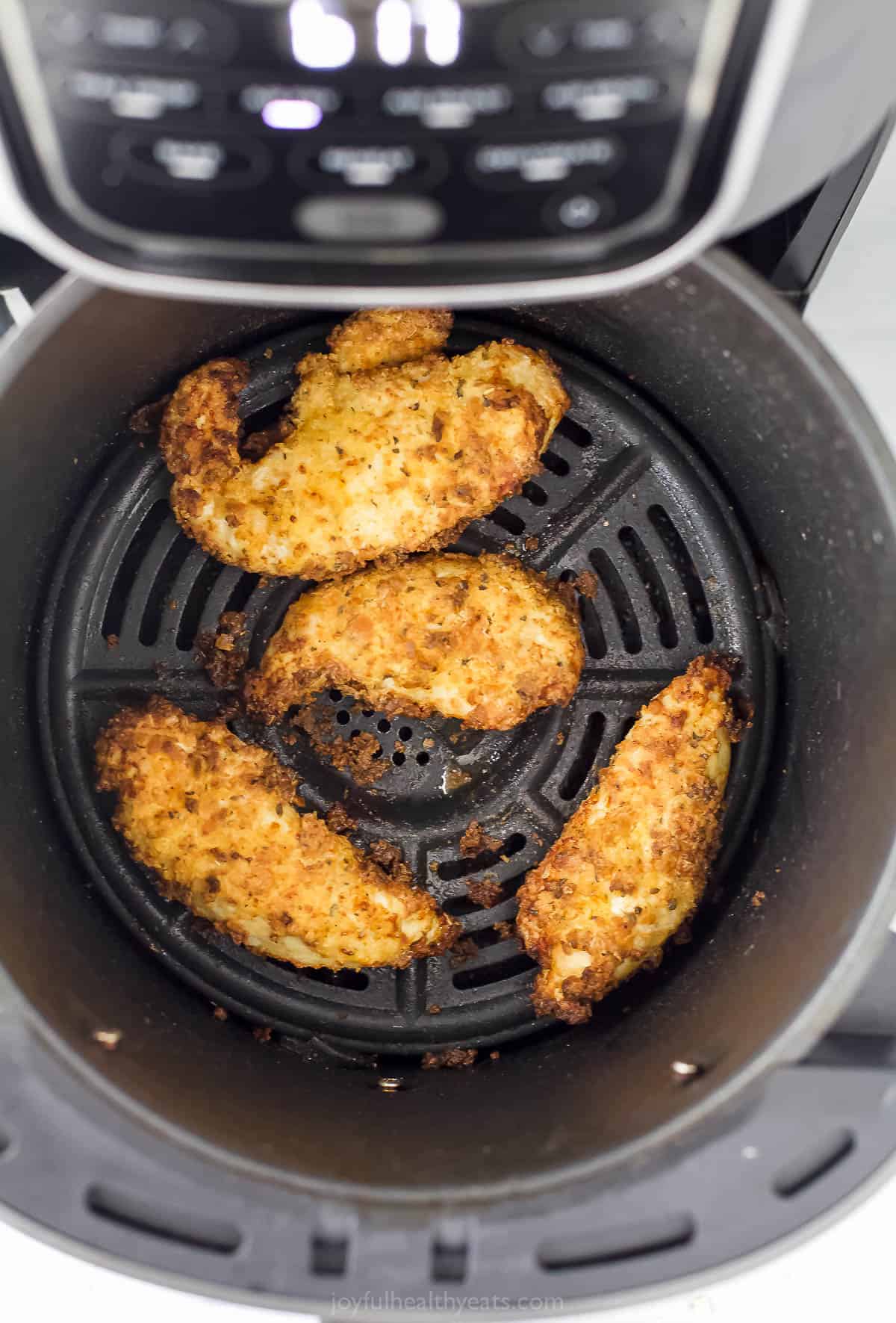 Four chicken tenders inside of a greased Air Fryer basket
