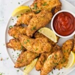 Air Fryer chicken strips on a plate with fresh lemon slices and ketchup