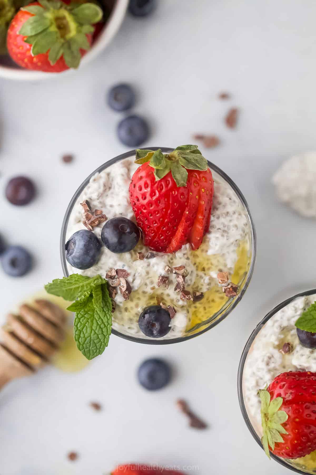 An overhead shot of a glass of chia seed pudding on a countertop beside another cup of pudding