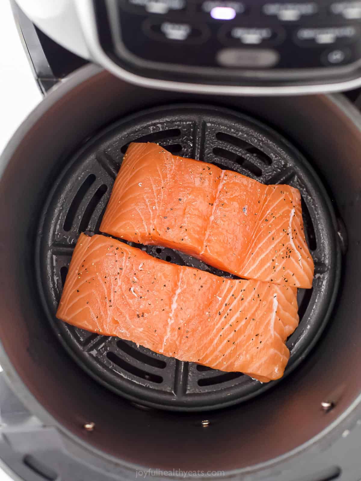 Two filets of salmon seasoned with salt and pepper.