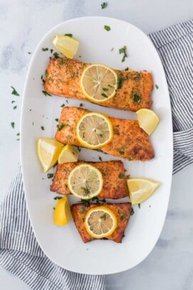 A white plate with 4 salmon fillets cooked in air fryer