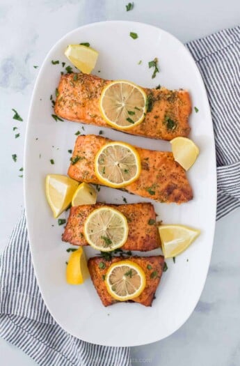 A white plate with 4 salmon fillets cooked in air fryer