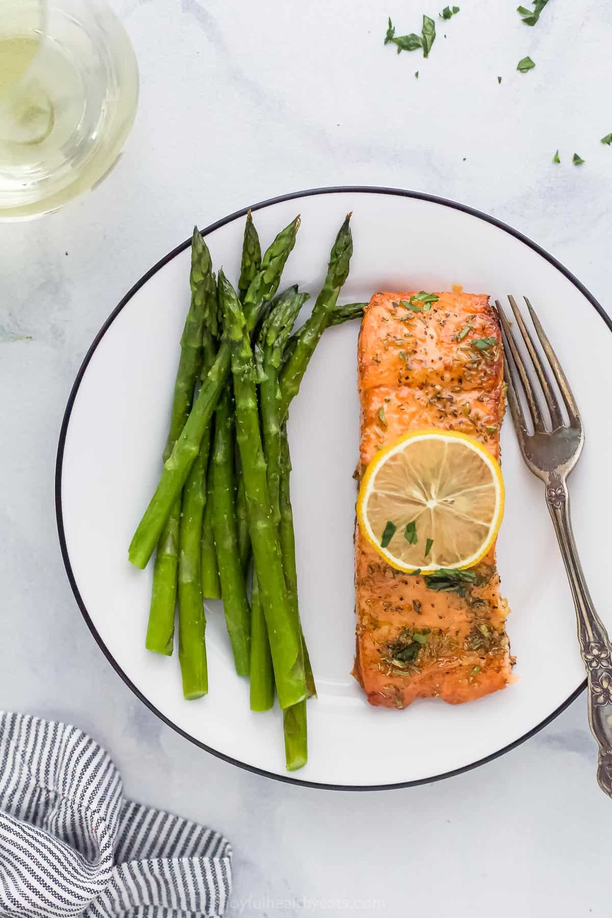 A white plate with air fryer salmon next to a serving of asparagus. 