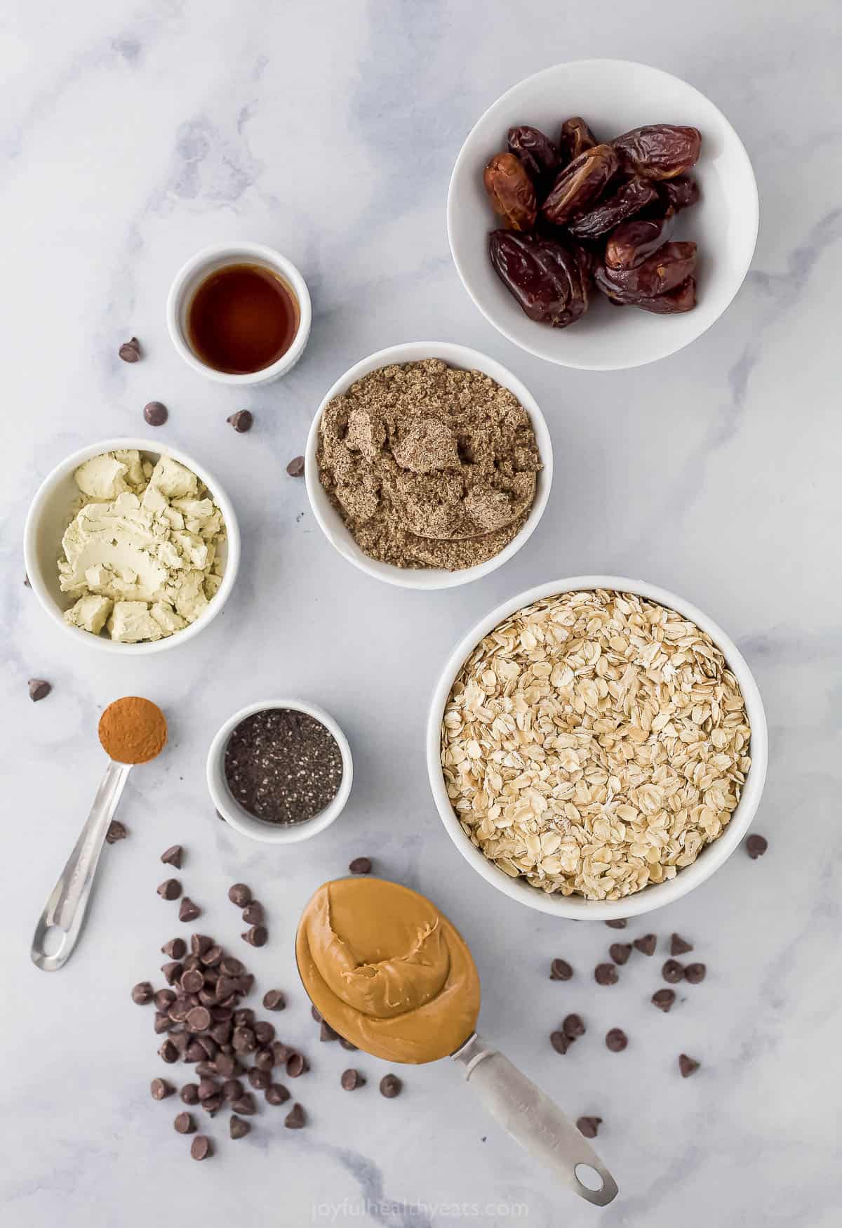 Dried dates, ground flax seed, chocolate chips, vanilla extract and the rest of the energy bite ingredients on a marble countertop