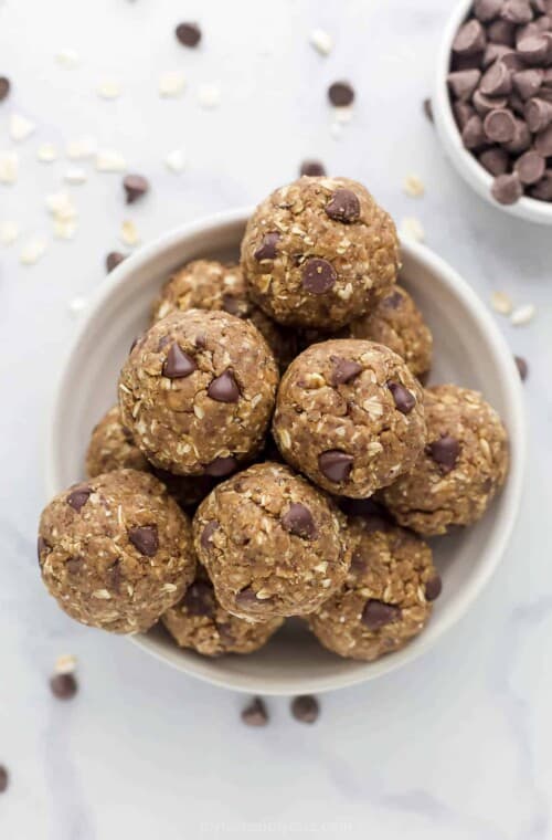 The bird's-eye view of a bowl of protein balls beside a smaller bowl filled with chocolate chips