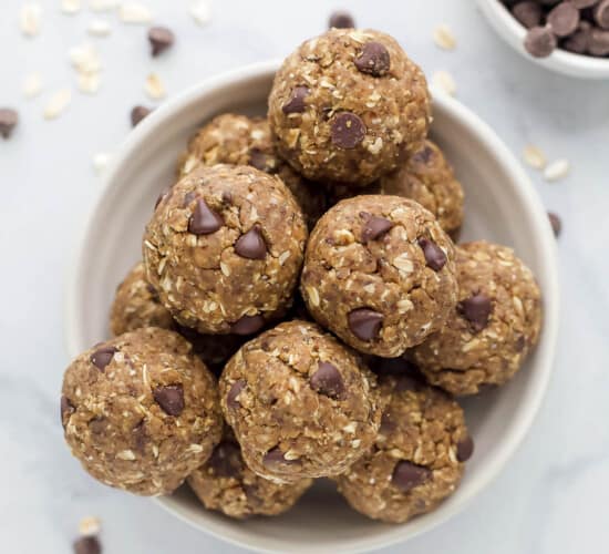 The bird's-eye view of a bowl of protein balls beside a smaller bowl filled with chocolate chips