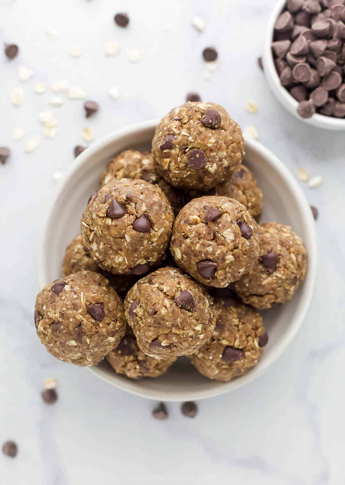 The bird's-eye view of a bowl of protein balls beside a smaller bowl filled with chocolate chips